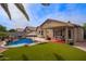 Inviting backyard featuring a pool with rock waterfall, covered patio, and lush artificial turf, perfect for relaxation at 3971 E Heather Ct, Gilbert, AZ 85234