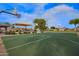 Outdoor basketball court with green surface, hoops, and a covered playground area on a sunny day at 3971 E Heather Ct, Gilbert, AZ 85234