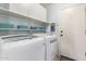 Bright laundry room featuring modern washer and dryer, storage shelves, and access door at 3971 E Heather Ct, Gilbert, AZ 85234