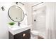 Bathroom with a round mirror, modern vanity, and a walk-in shower featuring white marble-look tiles at 4310 E Sacaton St, Phoenix, AZ 85044