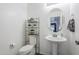Simple bathroom with a pedestal sink, toilet, and decorative shelf, maximizing space in a clean and functional design at 45543 W Guilder Ave, Maricopa, AZ 85139