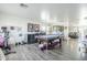 Open-concept game room featuring a pool table, gym equipment, and seamless connection to the living area at 45543 W Guilder Ave, Maricopa, AZ 85139