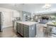 Open kitchen features gray cabinets, marble countertops, stainless appliances, and a view into the living room at 45543 W Guilder Ave, Maricopa, AZ 85139