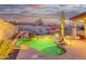 Backyard with a uniquely shaped pool, waterfall, desert landscaping, and a covered patio, lit by dramatic nighttime lights at 4615 S Primrose Dr, Gold Canyon, AZ 85118