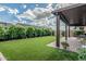 Spacious backyard featuring artificial grass, a covered patio, and lush green trees at 5653 E Sayan St, Mesa, AZ 85215