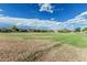 Expansive open field with green grass and scattered trees under a blue sky with fluffy white clouds at 5653 E Sayan St, Mesa, AZ 85215