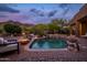 Desert backyard pool featuring a spa, rock waterfall, fire bowls, and lush landscaping against a mountain backdrop at 5690 E Canyon Creek Cir, Carefree, AZ 85377