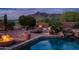 Beautiful pool area with a fire pit, rock features, and lush desert landscaping, ideal for entertaining at 5690 E Canyon Creek Cir, Carefree, AZ 85377