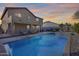 A backyard oasis showcasing a sparkling pool, patio furniture, and a covered outdoor living area at twilight at 5826 W Plum Rd, Phoenix, AZ 85083