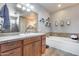 Bright bathroom featuring double sinks, a soaking tub, and decorative shelving for a relaxing and functional space at 5826 W Plum Rd, Phoenix, AZ 85083