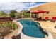Refreshing swimming pool with red lounge chairs and umbrella, surrounded by desert landscaping and a hot tub at 5978 E Chuckwalla Trl, Cave Creek, AZ 85331