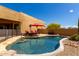 Inviting swimming pool with lounge chairs, desert landscaping, and a red umbrella for shade, creating a relaxing outdoor space at 5978 E Chuckwalla Trl, Cave Creek, AZ 85331