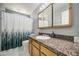 Bathroom with granite vanity, shower with curtain, and large vanity mirror at 6939 W Cambridge Ave, Phoenix, AZ 85035