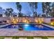 Sparkling swimming pool with travertine deck, grassy areas, and elegant lighting for evening enjoyment at 7438 E San Jacinto Dr, Scottsdale, AZ 85258