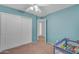 Bedroom with a ceiling fan and neutral carpet featuring closet and play pen at 780 S Lagoon Dr, Gilbert, AZ 85233