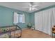Bright bedroom with aqua colored walls featuring a ceiling fan, neutral carpet, window and play pen at 780 S Lagoon Dr, Gilbert, AZ 85233