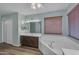 Bright bathroom with vanity, large mirror, wood blinds, and soaking tub, creating a spa-like experience at 780 S Lagoon Dr, Gilbert, AZ 85233