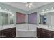 Well-lit primary bathroom featuring dual vanities, a corner soaking tub, and wood blinds for a serene atmosphere at 780 S Lagoon Dr, Gilbert, AZ 85233