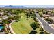 Expansive aerial view of a neighborhood showcasing lush green spaces and mountain views at 10234 E Lomita Ave, Mesa, AZ 85209
