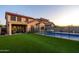 A stunning backyard features pool, hot tub, covered patio, artificial grass, and desert landscaping at 10850 W Bronco Trl, Peoria, AZ 85383