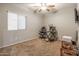 This carpeted bedroom includes a ceiling fan, a bright window, and a simple desk setup at 10850 W Bronco Trl, Peoria, AZ 85383