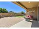 Relaxing covered patio with stone flooring, cozy seating, and a well-manicured backyard at 13811 W Paso Trl, Peoria, AZ 85383