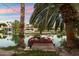 Picturesque waterfront property with a private dock, boat, lush landscaping, and mature palm trees at 1507 E Treasure Cove Dr, Gilbert, AZ 85234