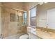 Bright bathroom featuring glass shower, travertine tile, granite vanity, and natural light from the window at 1507 E Treasure Cove Dr, Gilbert, AZ 85234