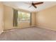 Empty bedroom featuring neutral walls, carpet and a window with green curtains at 18417 W Elm St, Goodyear, AZ 85395