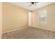 This carpeted bedroom features a ceiling fan, neutral walls, and a sunlit window at 18417 W Elm St, Goodyear, AZ 85395