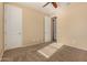 This carpeted bedroom includes a ceiling fan, neutral walls, and closet at 18417 W Elm St, Goodyear, AZ 85395
