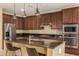 Modern kitchen with granite countertops, stainless steel appliances, and dark wood cabinetry at 18417 W Elm St, Goodyear, AZ 85395