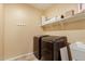 This laundry room features side-by-side washer/dryer, utility sink, and storage shelves at 18417 W Elm St, Goodyear, AZ 85395