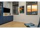 Modern living room featuring custom blue cabinetry with marble backsplash and sunset views through black grid windows at 2 Biltmore Est # 309, Phoenix, AZ 85016