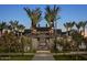 Community entrance featuring palm trees and a well-manicured landscape at dusk at 2024 W Trotter Trl, Phoenix, AZ 85085