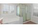 Bright bathroom features a tiled floor, bathtub, glass shower, and window with blinds at 21950 N Dietz Dr, Maricopa, AZ 85138