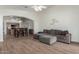 Open-concept living room and kitchen featuring wood-look tile flooring and neutral decor with grey sectional couch at 21950 N Dietz Dr, Maricopa, AZ 85138