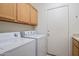 Functional laundry room featuring white appliances, cabinetry, and a doorway to the exterior at 22231 N 51St St, Phoenix, AZ 85054