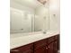 Well-lit bathroom vanity featuring dark wood cabinets, a white countertop, and a large mirror at 25212 W Maldonado Dr, Buckeye, AZ 85326