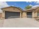 The large three-car garage complements this tan single-story home with its well-maintained desert landscape on a beautiful sunny day at 25212 W Maldonado Dr, Buckeye, AZ 85326