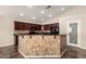 Open kitchen featuring dark wood cabinets, granite countertops, and a mosaic-tiled island with bar seating at 25212 W Maldonado Dr, Buckeye, AZ 85326