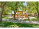 Community playground featuring slides, climbing structures, and a playful car, all set in a green, tree-shaded area at 26071 W Sequoia Dr, Buckeye, AZ 85396