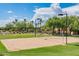 Sand volleyball court with net in a well-kept community area, surrounded by green grass and trees at 26071 W Sequoia Dr, Buckeye, AZ 85396