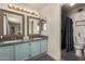 Bathroom featuring a double vanity with blue cabinets and a walk-in shower with contemporary fixtures at 2643 E Menlo St, Mesa, AZ 85213