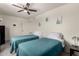 Bright bedroom featuring two twin beds with blue quilted bedding, cactus art, and a ceiling fan at 2643 E Menlo St, Mesa, AZ 85213