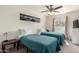 Comfortable bedroom showcasing two twin beds with blue quilts, a ceiling fan, and a view from the window at 2643 E Menlo St, Mesa, AZ 85213