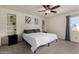 Cozy bedroom features neutral walls, carpet, a ceiling fan, and built-in shelves for ample storage and display at 2643 E Menlo St, Mesa, AZ 85213