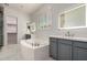 Primary bathroom featuring double vanities, a soaking tub, modern lighting, and a separate glass enclosed shower at 26860 N 102Nd Ln, Peoria, AZ 85383