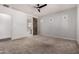 Spacious bedroom featuring a ceiling fan, neutral carpeting, and a sliding barn door leading to the ensuite bathroom at 26860 N 102Nd Ln, Peoria, AZ 85383