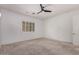 Bright bedroom featuring carpeted floor, a ceiling fan, modern window shutters, and a white door at 26860 N 102Nd Ln, Peoria, AZ 85383